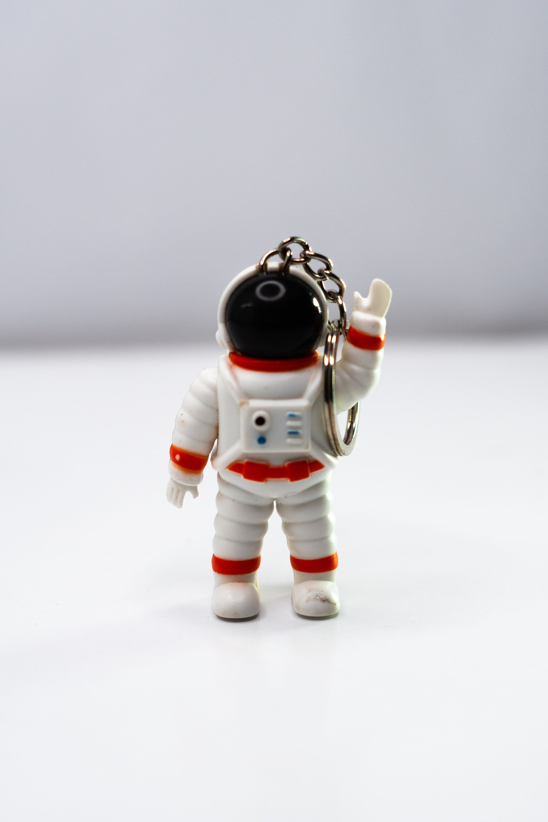 Cute astronaut keychain waving to the camera on a white background